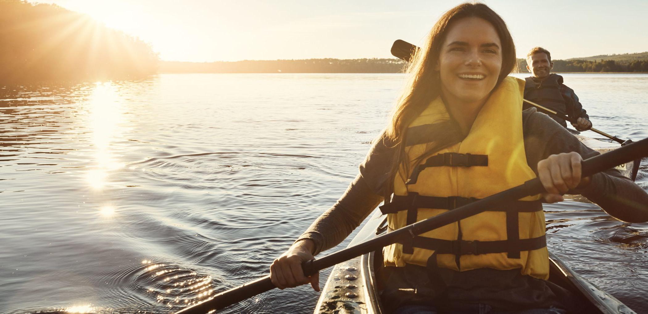 微笑的Patelco客户在日落时分在海湾上划独木舟.