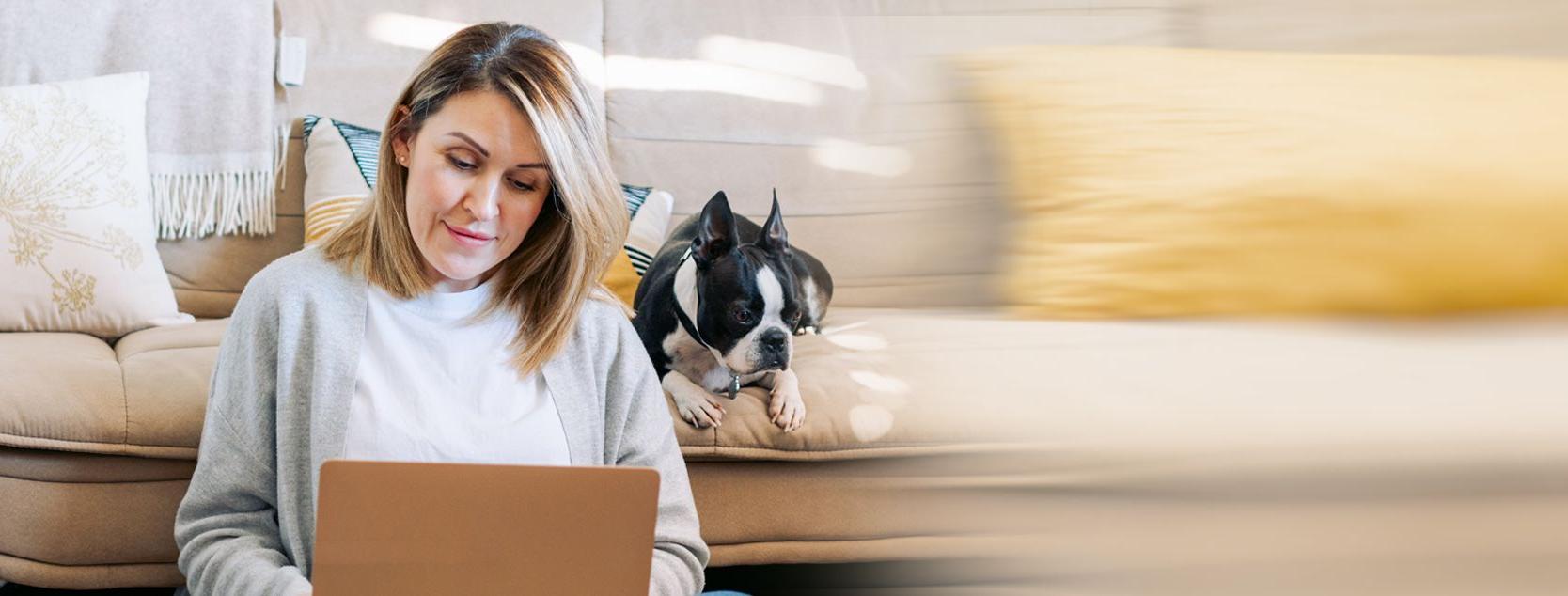 A woman manages her bank accounts from her laptop as her dog watches on